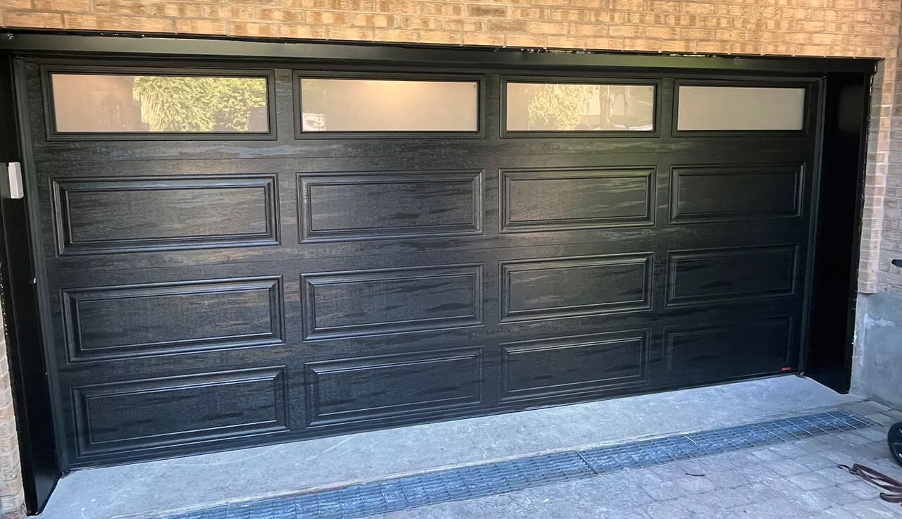 Porte de garage noire avec fenêtres, offrant un design classique et élégant.